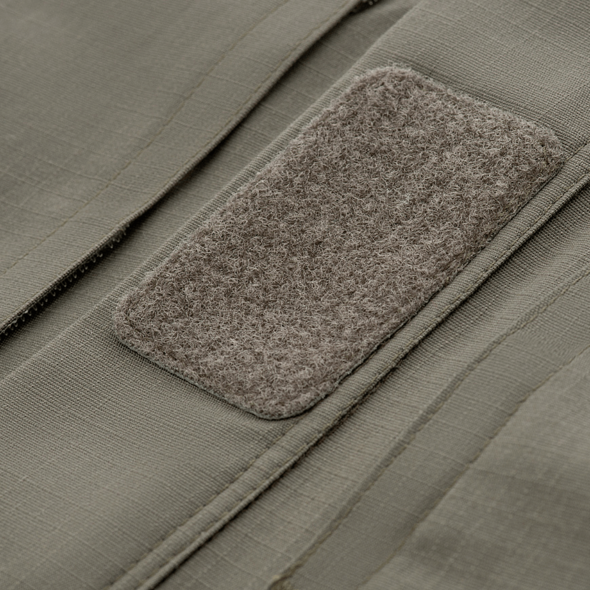 Nærbillede af velcro-panel på M-Tac Jakke Patrol Flex, laveret grå stof med ripstop mønster og taktisk design.