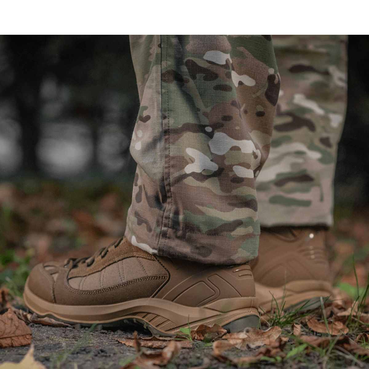M-Tac Feltbukser NYCO i camouflagemønster, fremstillet af slidstærkt NYCO-stof, vises med kraftige støvler på skovbund.