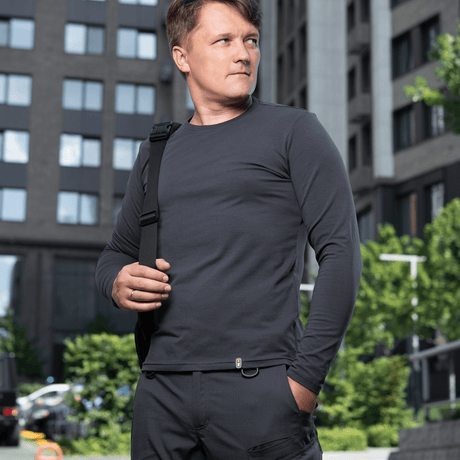 Mand i en M-Tac Long-sleeve T-shirt 93/7 foran en bybaggrund, ideel til hverdagen, uniformer, sport og friluftsliv.