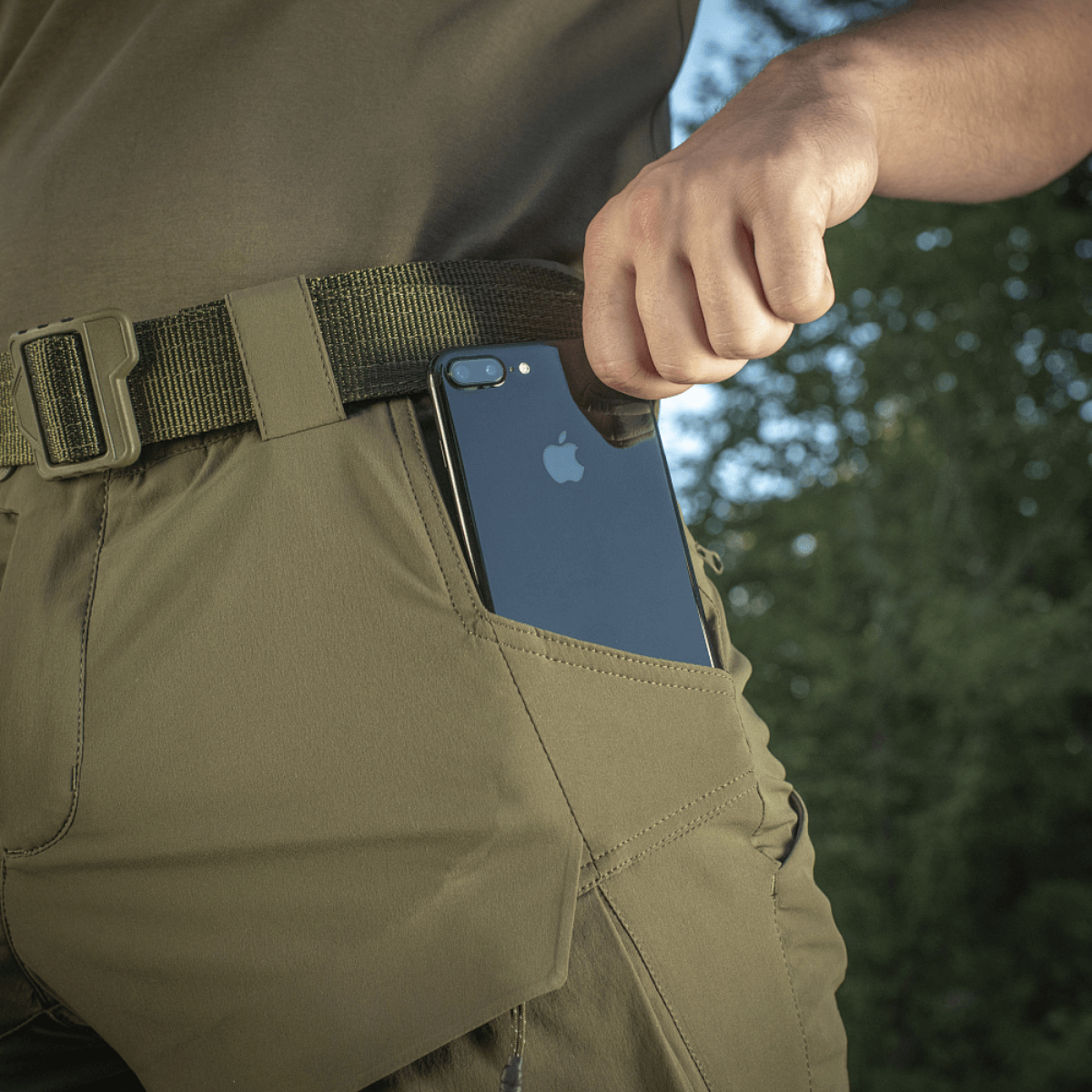 M-Tac Shorts Rubicon Flex med en mobiltelefon i cargo-lommen, designet til sommertid komfort og funktionalitet i mørk olivenfarve.