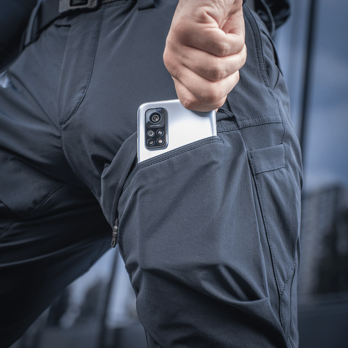 M-Tac Bukser Rubicon Flex i brug med telefon i innovativ cargo-lomme, viser praktisk design og fuld bevægelsesfrihed.