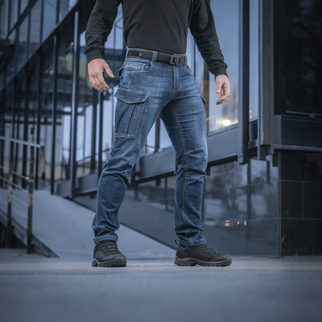 M-Tac Jeans Aggressor i slidstærkt denim med rummelige lommer og taktisk funktionalitet, set udendørs med moderne stil.