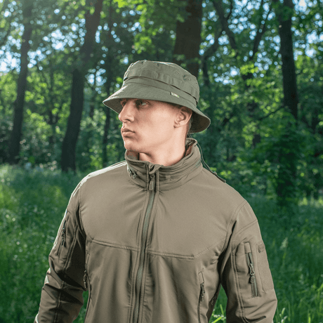 Mand iført M-Tac Panama Rip-Stop army-hat med semi-stiv skygge og ventilationshuller, stående i en skov. Inspireret af Boonie-model.