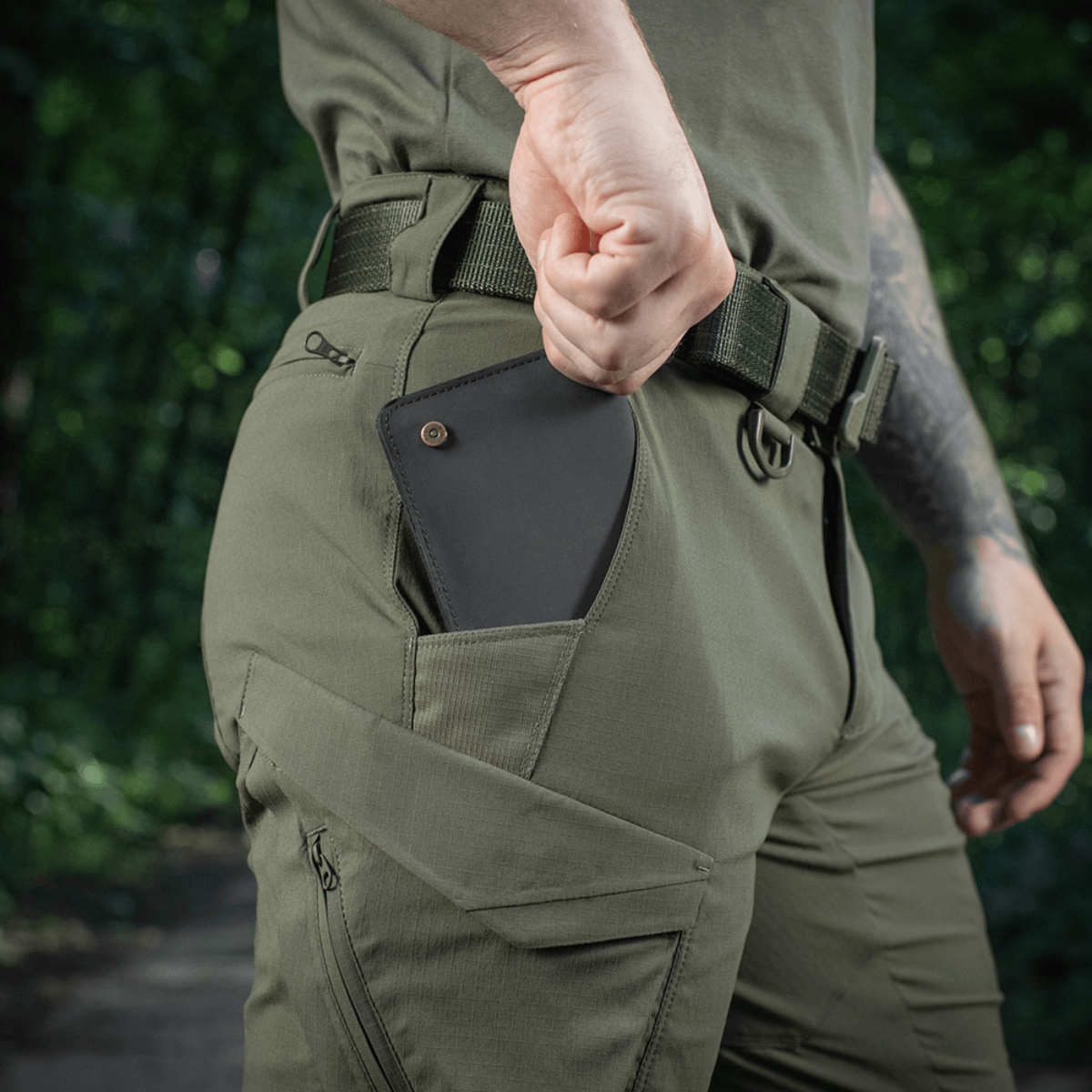 M-Tac Aggressor Summer Flex Shorts i grønt, viser praktisk lomme med smartphone, ideel til udendørs aktiviteter og friluftsliv.