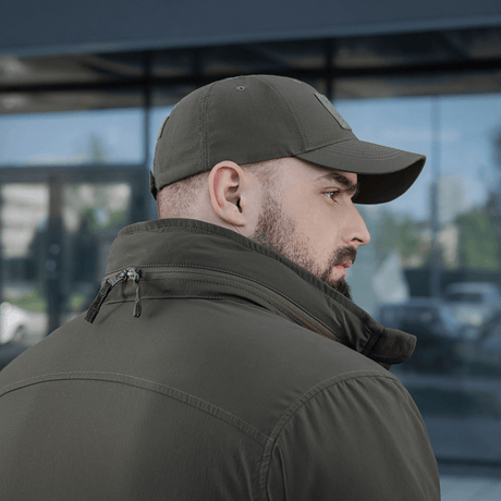 M-Tac Flash Jakke set bagfra, ideel til vandreture og sport, i et praktisk design uden velcrofelter, bæres af en mand med kasket.