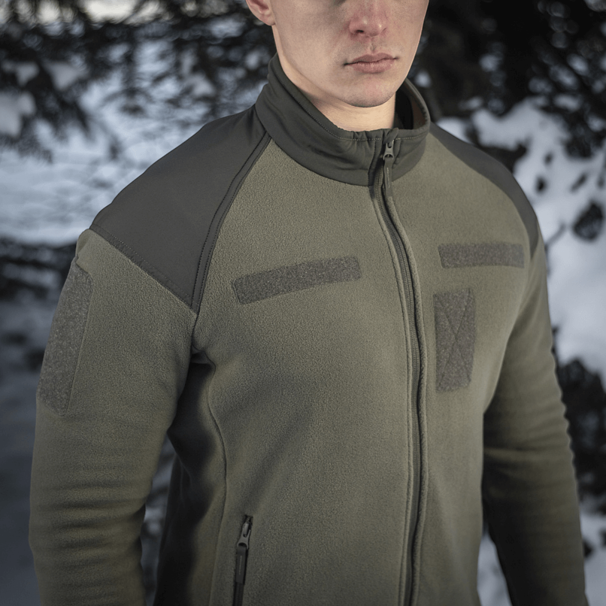 Mand iført M-Tac Combat Fleece Jakke i skov, vintermiljø, moderne design, vindafvisende stof, Himates fleece