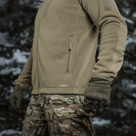 M-Tac Combat Fleece Polartec Jakke, slidstærk fleecejakke med YKK lynlåse og velcrolukning, perfekt til taktisk brug, set i naturmiljø.