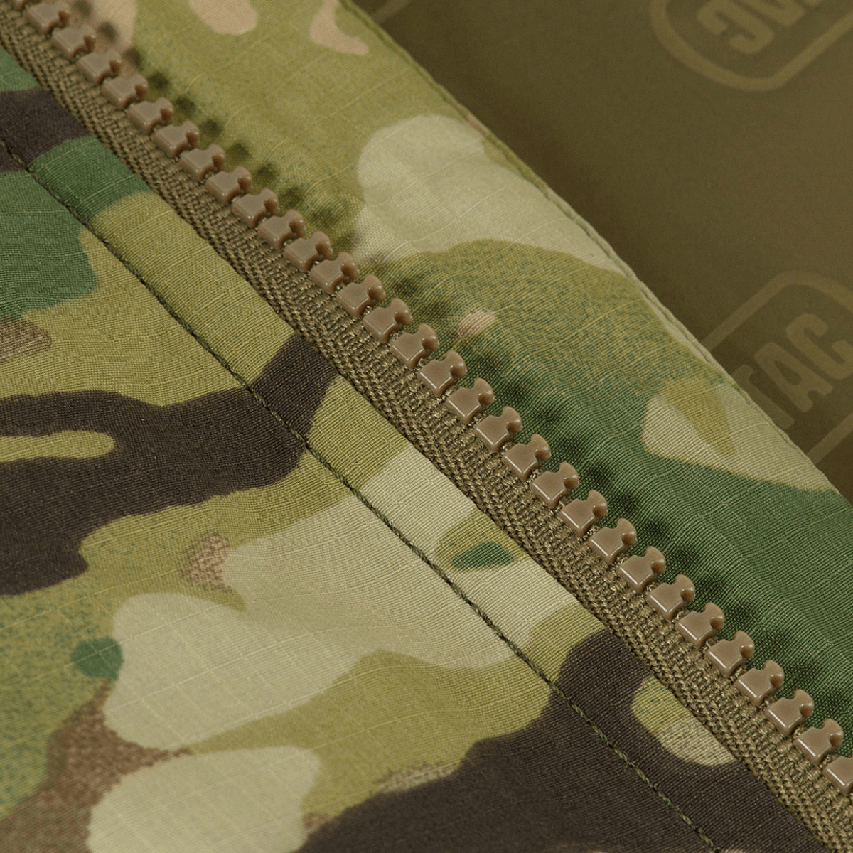 Detalje af M-Tac Alpha Gen.IV Pro Primaloft Vinterjakke med Multicam stof og lynlås.