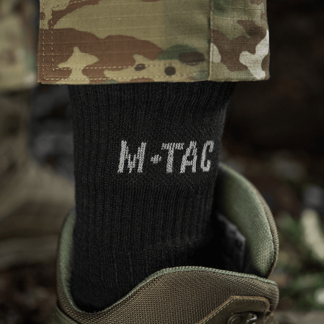 M-Tac Sokker Winter Wool i sort, fremstillet af merinould, bæres i militærstøvler, ideelle til vinterbrug for maksimal varme og komfort.