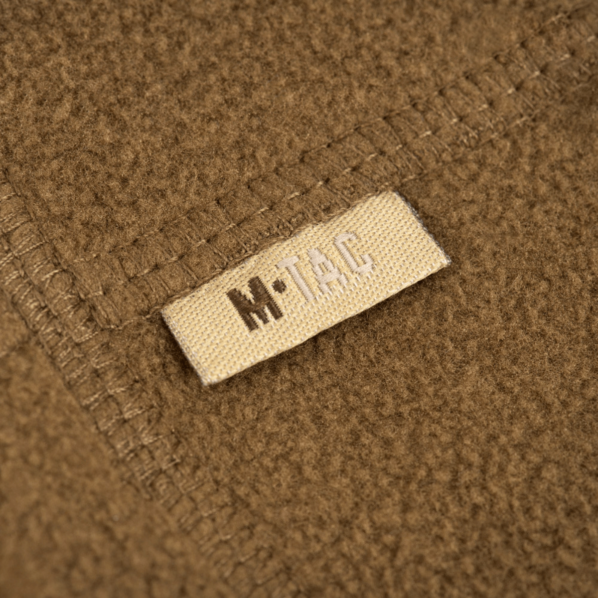 Et nærbillede af M-Tac Fleece Neck Gaiter med Snor, viser det bløde fleece-materiale og mærkelappen.