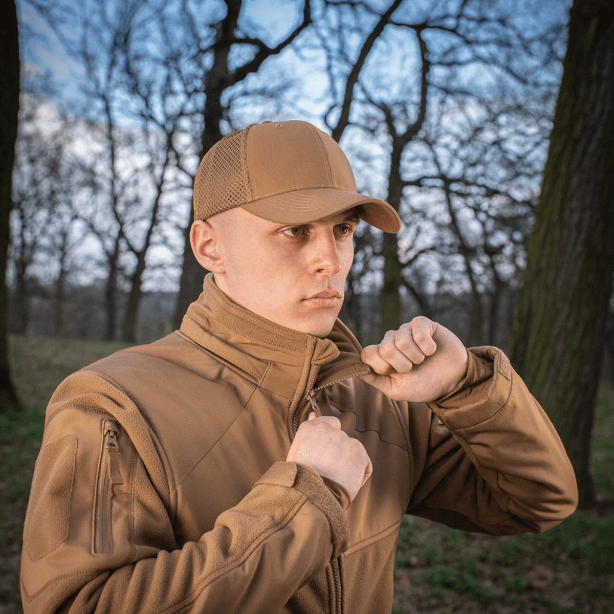 Mand iført M-Tac Mesh Flex Ripstop Baseball Cap i en skov, viser praktisk og holdbar sørge for komfort og ventilation til udendørs aktiviteter.