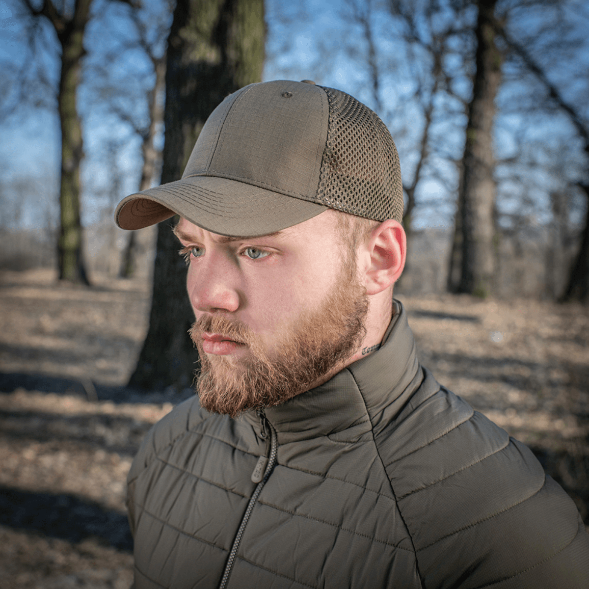Mand iført M-Tac Mesh Flex Ripstop Baseball Cap i naturen, viser mesh-paneler og holdbar skygge, ideel til udendørs brug.