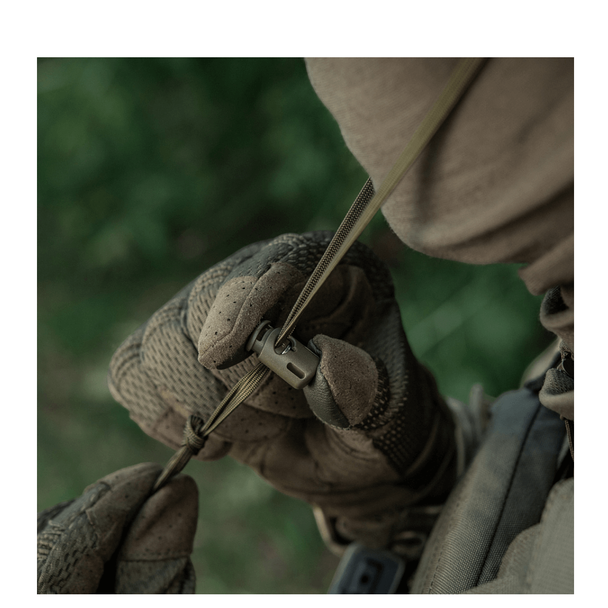 Person iført camouflagetøj justerer et spænde på en M-Tac Panamahat Gen. II Summer Flex i naturmiljø