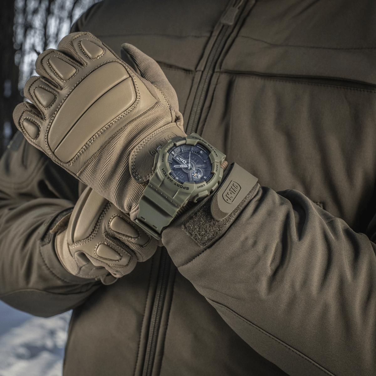M‑Tac Sport Ur med robust design, perfekt til outdoor-aktiviteter, vist på arm med handsker i vinterlandskab.