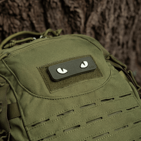 M-Tac Cat Eyes 3D PVC Patch på grøn rygsæk ved siden af træ