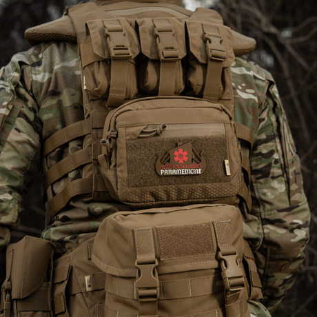 Taktisk rygsæk med 'Paramedicine' patch i camouflagemønster set bagfra i naturen, robust og holdbar til udendørs brug
