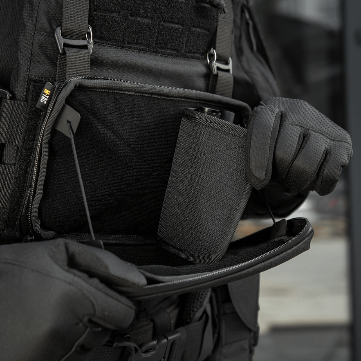 Person åbner M-Tac Admin Pouch Large Elite Gen.II med et stort rum til opbevaring af gear, fremstillet af robust Cordura 500D.