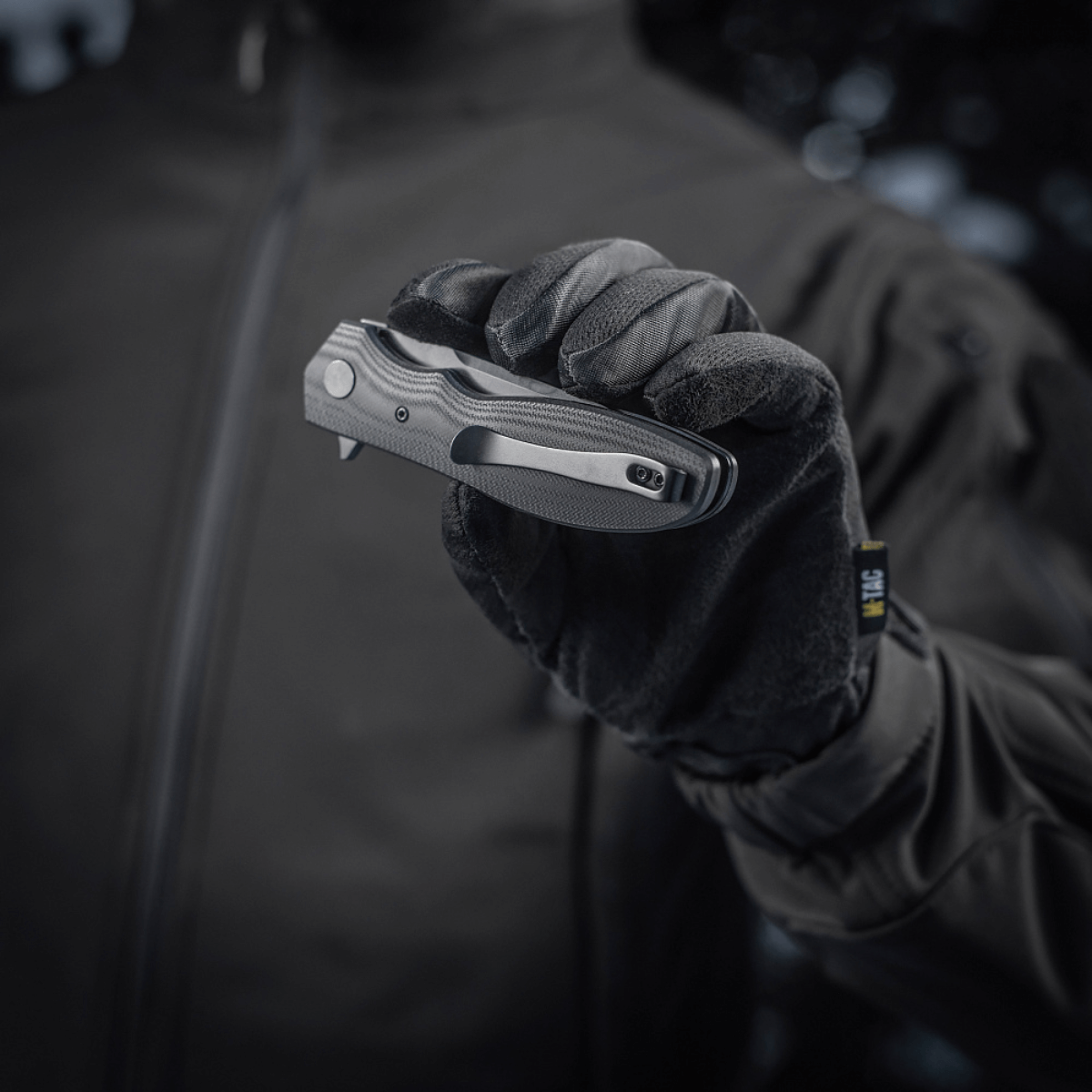 Person holding M-Tac Outdoor & Militær foldekniv - Type 6 with black G10 composite handle in gloved hand