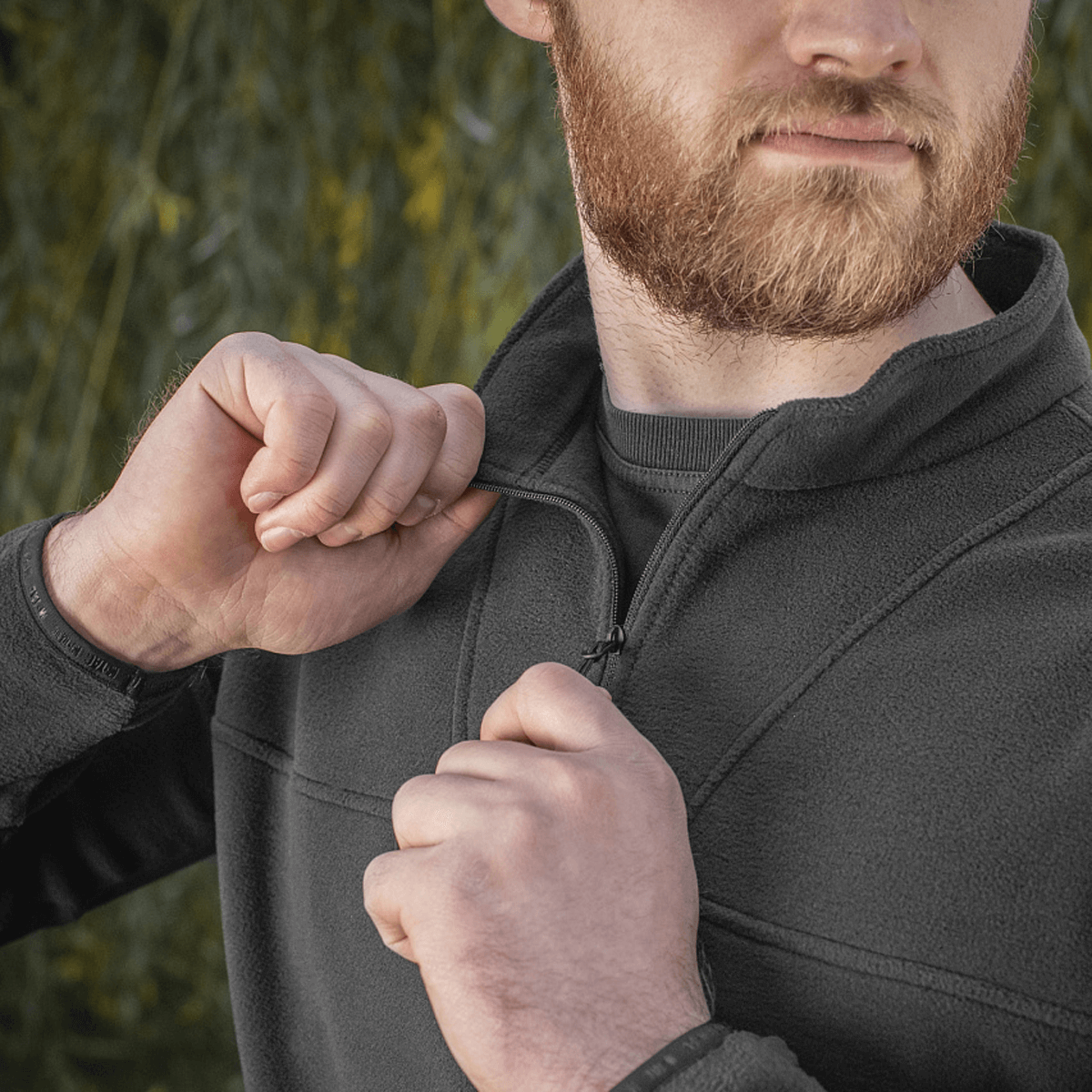 Mand iført M-Tac Delta Polartec Fleecejakke med halv lynlås, ideel til kolde dage, fremstillet af let og varmt Polartec® Micro Series-fleece.