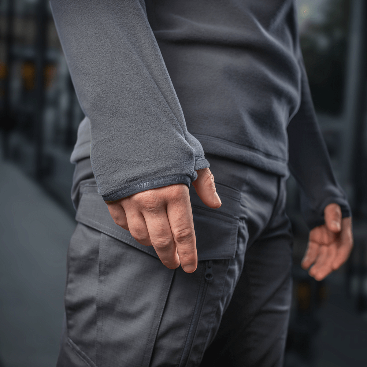 Person iført M-Tac Delta Polartec Fleecejakke viser halv lynlås funktion i gråt stof, designet til kolde dage.