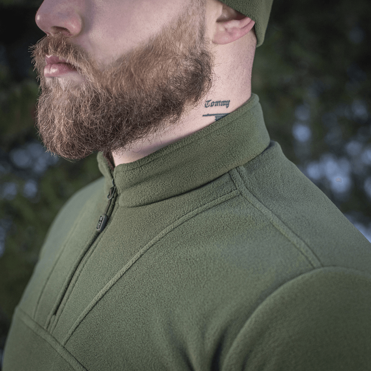 Mand iført M-Tac Delta Polartec Fleecejakke i skovgrøn farve med halv lynlås, ideel til kolde dage, åndbar og varm.