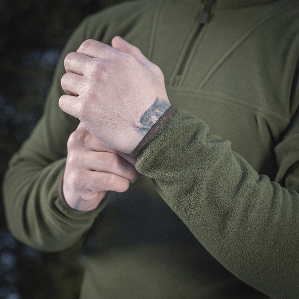 Mand iført M-Tac Delta Polartec Fleecejakke i oliven, tæt på visning af manchet og lynlås, ideel til kolde dage.