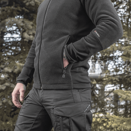 Mand iført M-Tac Polartec Sport Fleecejakke i skov, viser jakken som et varmt og funktionelt mellemlag i koldt vejr.