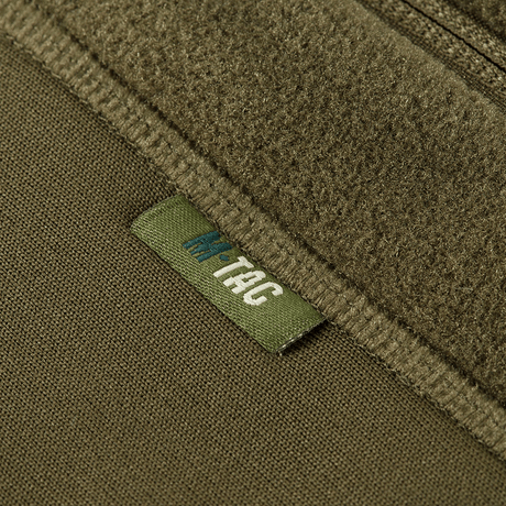 Close-up af M-Tac Polartec Sport Fleecejakke i grøn farve med synligt brandmærke.