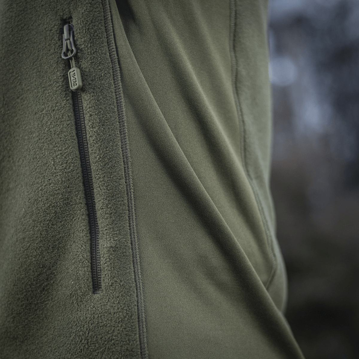 Nærbillede af M-Tac Polartec Sport Fleecejakke med lynlås i naturen, viser premium varmeisolering og åndbarhedsmateriale.