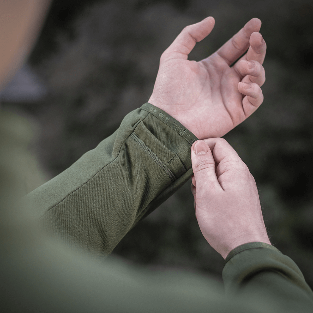 Nærbillede af en person, der justerer en ærme på M-Tac Polartec Sport Fleecejakke, fokus på materialets fleksibilitet og komfort.