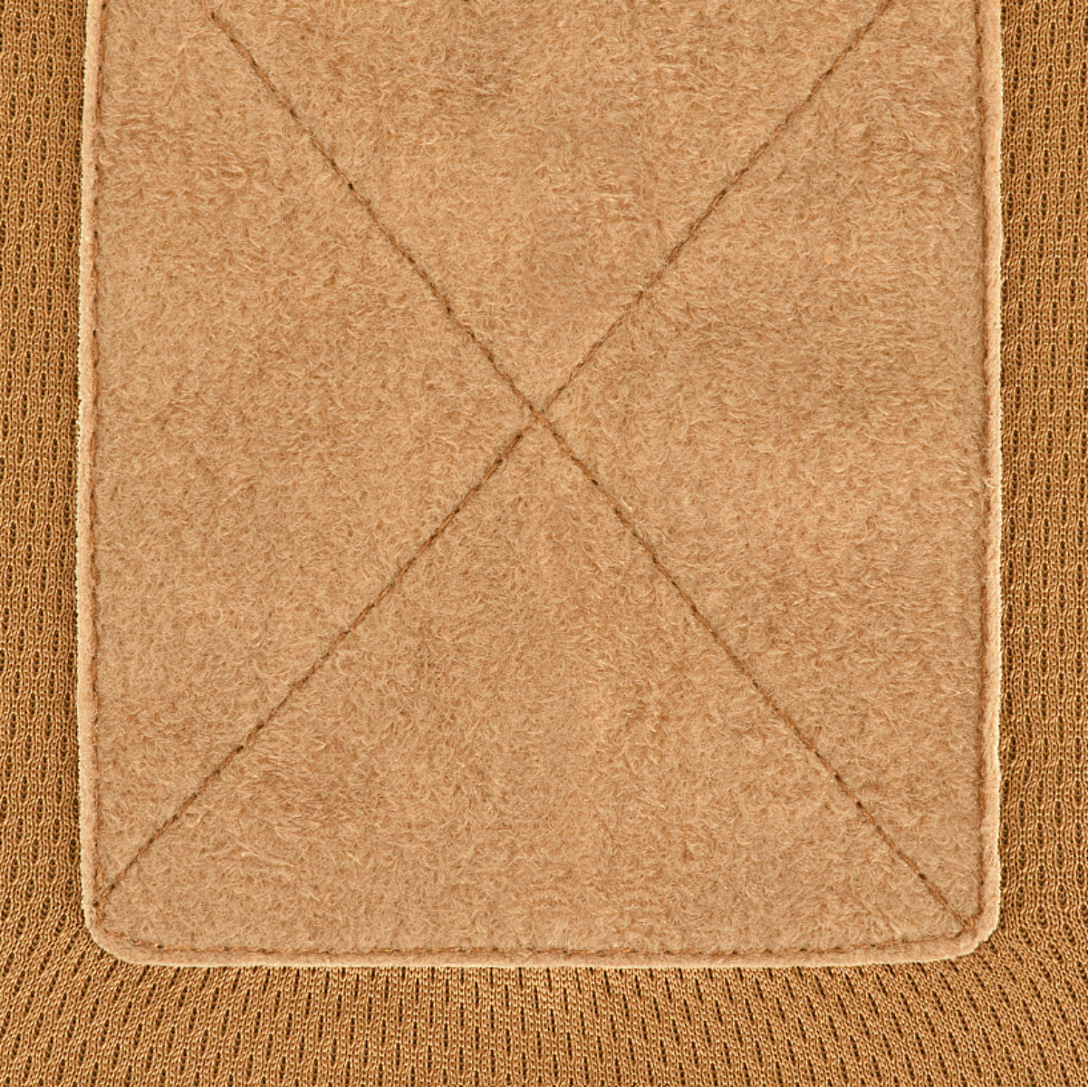 Detaljeret nærbillede af beige stoftekstur med krydsende syningslinjer, der viser materialekvalitet og design.