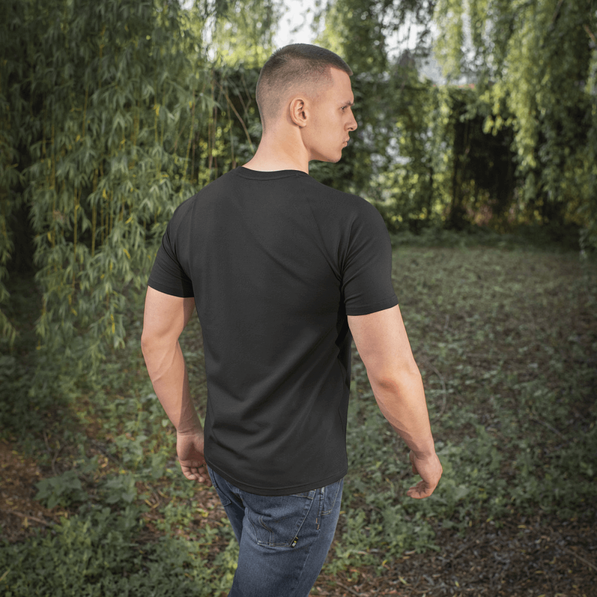 Mand iført en M-Tac Raglan T-Shirt 93/7 med komfortable raglanærmer i en naturlig udendørs omgivelser.