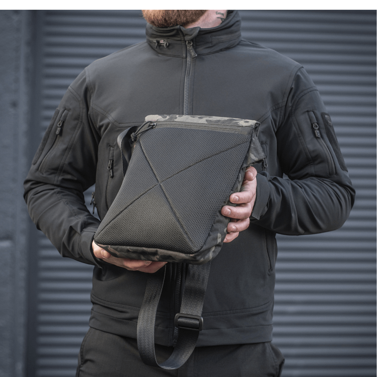 Mand holder en M-Tac Konvert Taske Elite lavet af Cordura 500D og Cordura Hex 1000D med justerbar skulderrem og magnetventil.