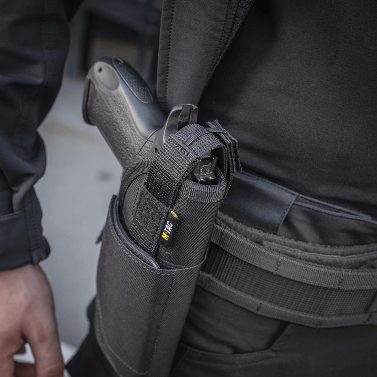 M-Tac Universal Taktisk Hylster Elite Højre monteret på bæltet med en pistol, viser justerbart og sikkert design med YKK og Velcro lukning.