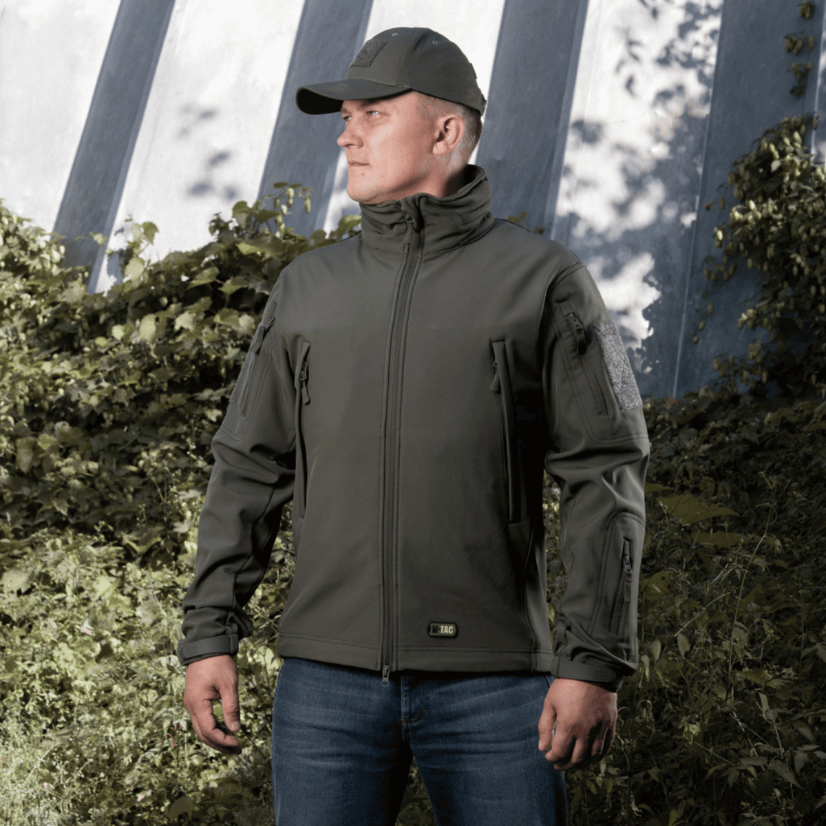 Mand iført M-Tac Soft Shell Jakke, ideel til vind og vejr, med fugtafvisende ydre og isolerende indre lag, designet til komfort og stil.