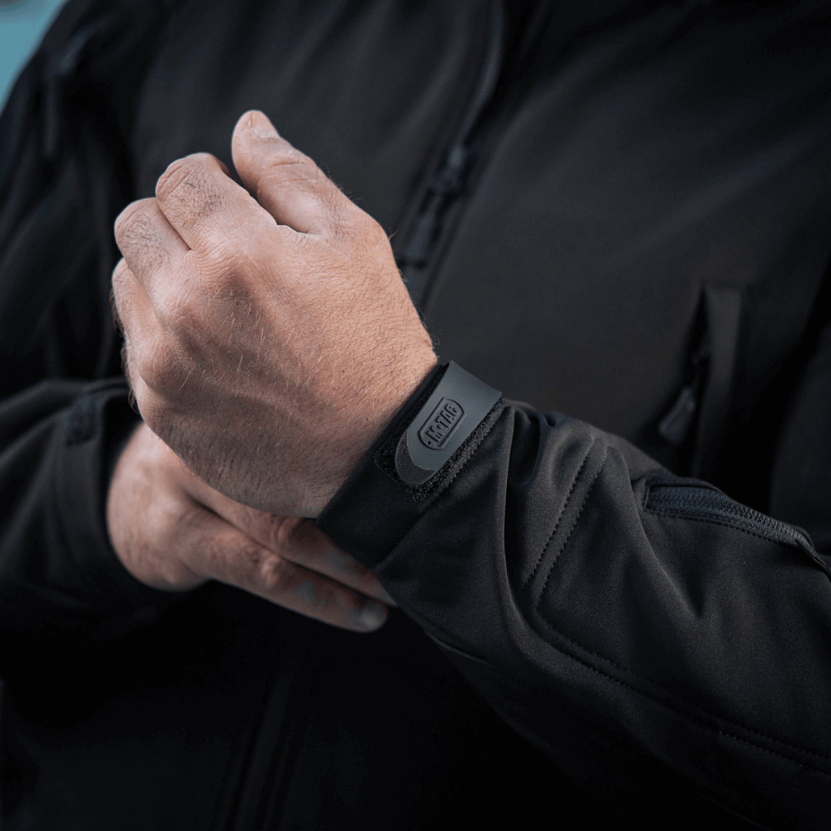 Person iført M-Tac Soft Shell Jakke med justerbar manchet, ideel til beskyttelse mod dårligt vejr med let fleece indvendigt.