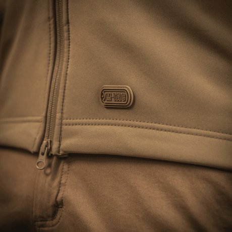 M-Tac Soft Shell Jakke i nært billede, fremhæver sit letvægtsdesign med polyuretan-membran og fleece-lag til vejrsikring.