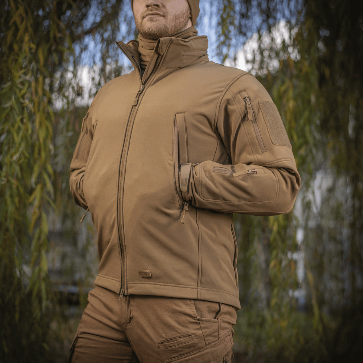 M-Tac Soft Shell Jakke i naturen, designet med en indre polyuretan-membran og fleece-lag til vejrbeskyttelse og komfort.