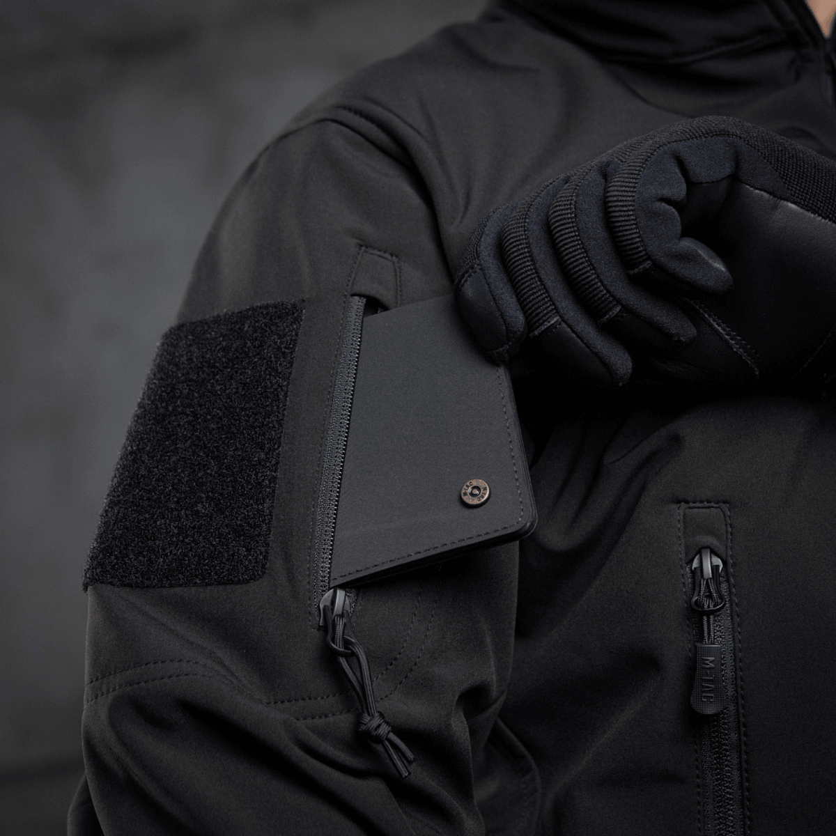 M-Tac Soft Shell Police Jakke med velcro identifikationspanel, justerbar hætte skjult i kraven og beskyttet mod vind og vejr.