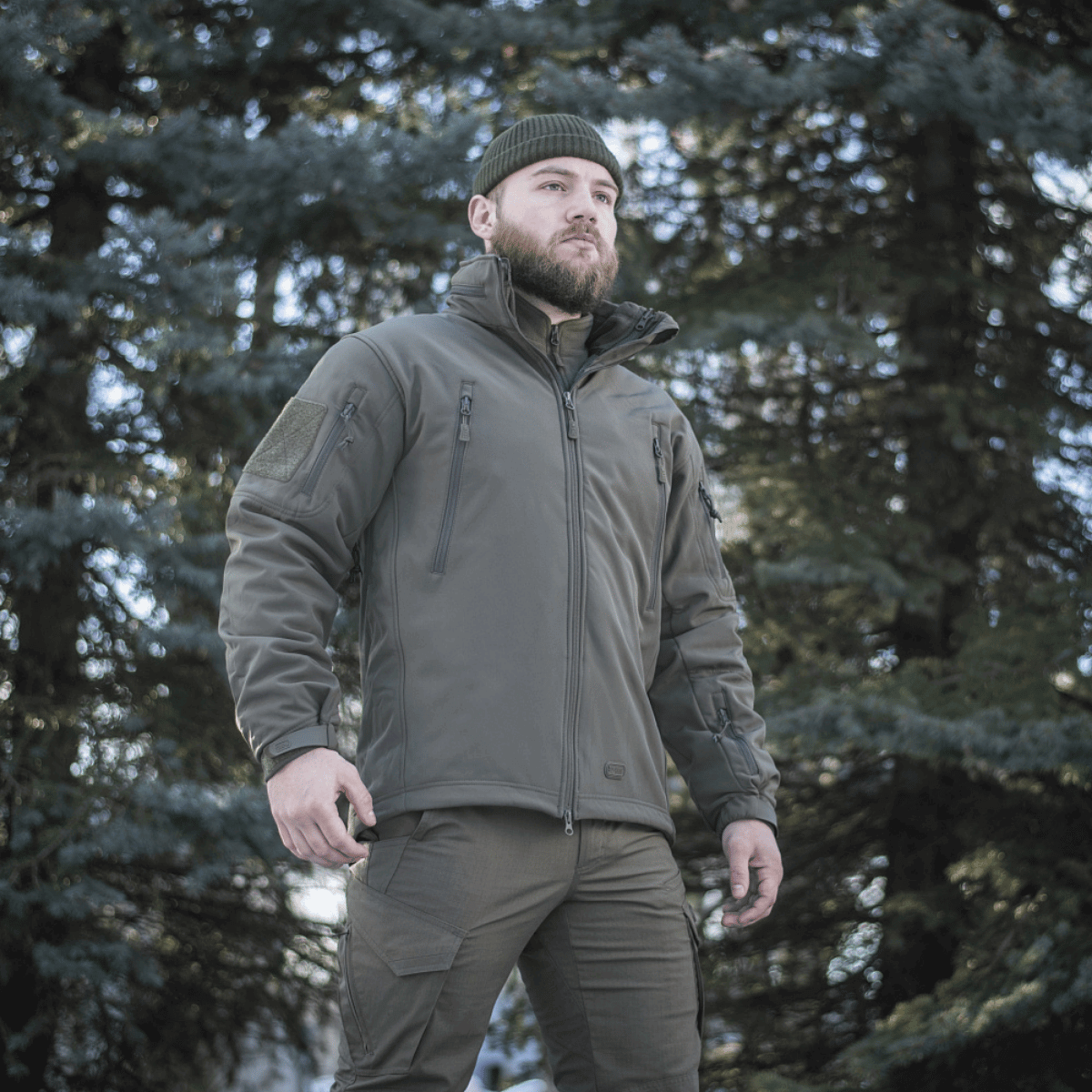 Mand iført M-Tac Soft Shell Jakke med Liner i skovområde, vinterbeklædning med aftageligt fleecefoer.