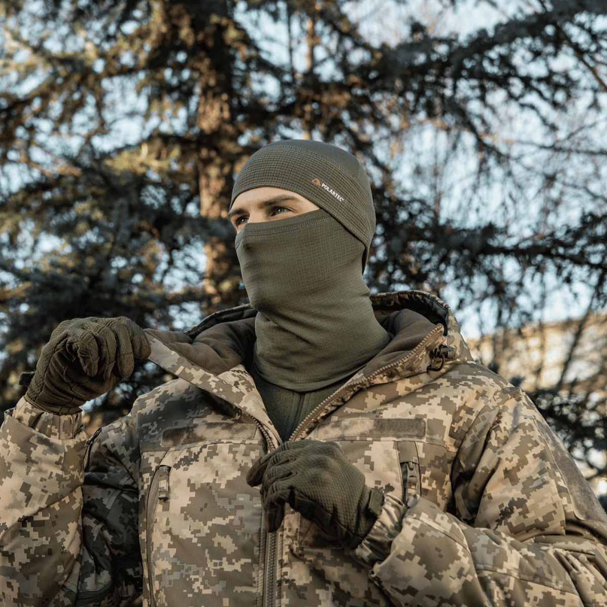 Mand iført M-Tac Tube Scarf Polartec Power Grid i camouflagejakke i skovmiljø, der viser alsidig anvendelse af halsrør.