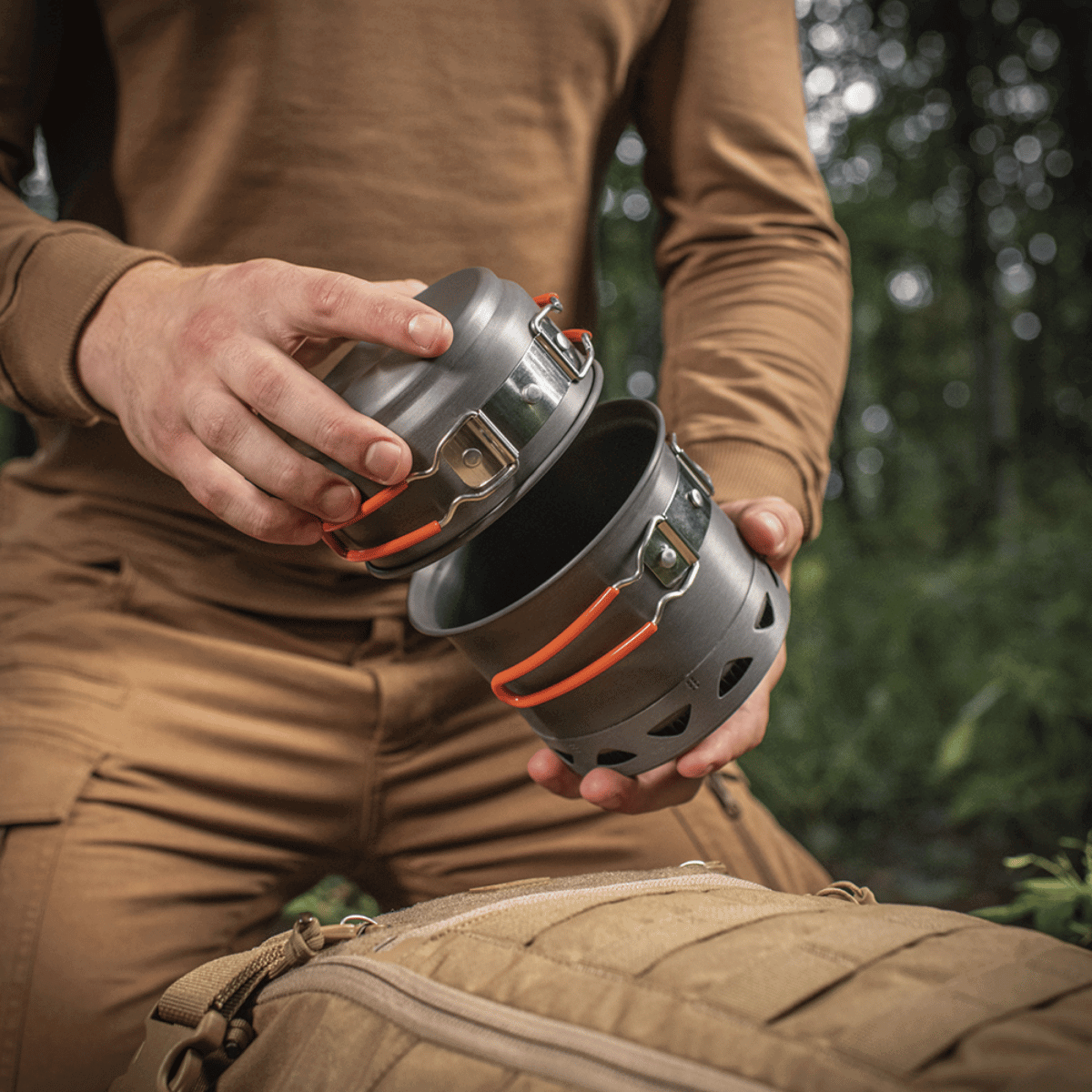 M-Tac Individuelt Kogesæt til Brænder i anodiseret aluminium, ideelt til friluftsliv og camping, holdt af person i udendørs miljø.