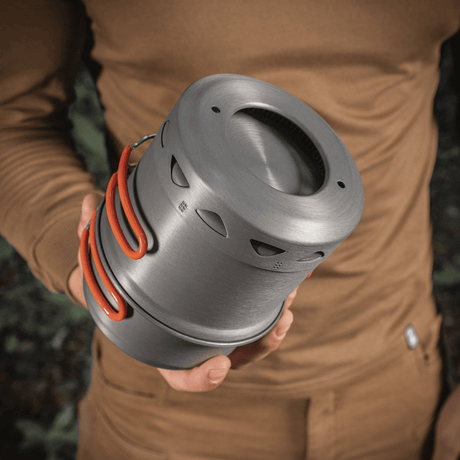 Person der holder et M-Tac Individuelt Kogesæt til Brænder i anodiseret aluminium, velegnet til camping og friluftsliv.