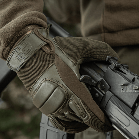 M-Tac Handsker Assault Tactical Mk.2 i brug, viser greb med ægte læder og støddæmpende inserts, ideel til taktisk anvendelse.