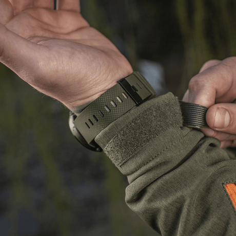 Person justerer M‑Tac Multifunktionelt Taktisk Ur, ideelt til militærbrug og friluftsliv, med robust urkasse og avancerede funktioner.