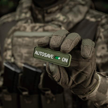 Taktisk operatør holder M-Tac Patch Autosave PVC 3D-morale patch med velcro, perfekt til tøj eller udstyr.