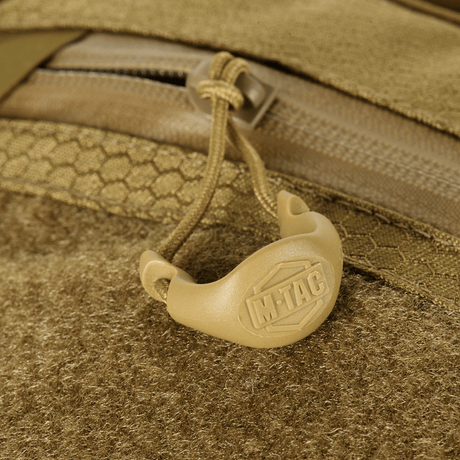 Detalje af M-Tac Sling Pistol Taske Elite Hex med Velcro, viser lynlås og håndtag med logo, lavet af slidstærk Cordura-materiale.