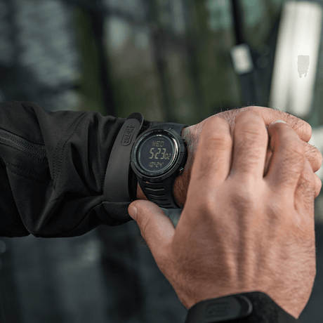 M-Tac Tactical Ur 2147 på håndled i naturen, robust design til outdoor og taktisk brug med funktioner som kompas og LED-belysning.