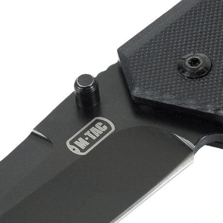 M-Tac Outdoor & Militær foldekniv - Type 5 med G10-komposit håndtag i nærbillede, viser rustfrit stål klinge og logo