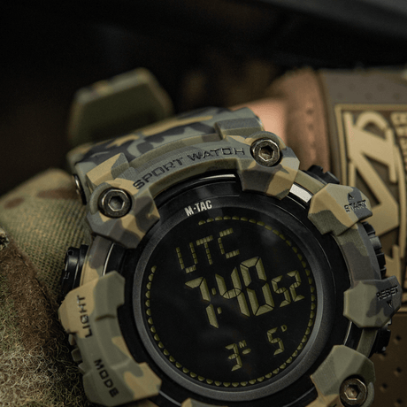 M-Tac Tactical Ur 2037 i robust camouflagedesign med LED-baggrundsbelysning og funktioner som kompas og stopur. Ideel til outdoor og taktisk brug.